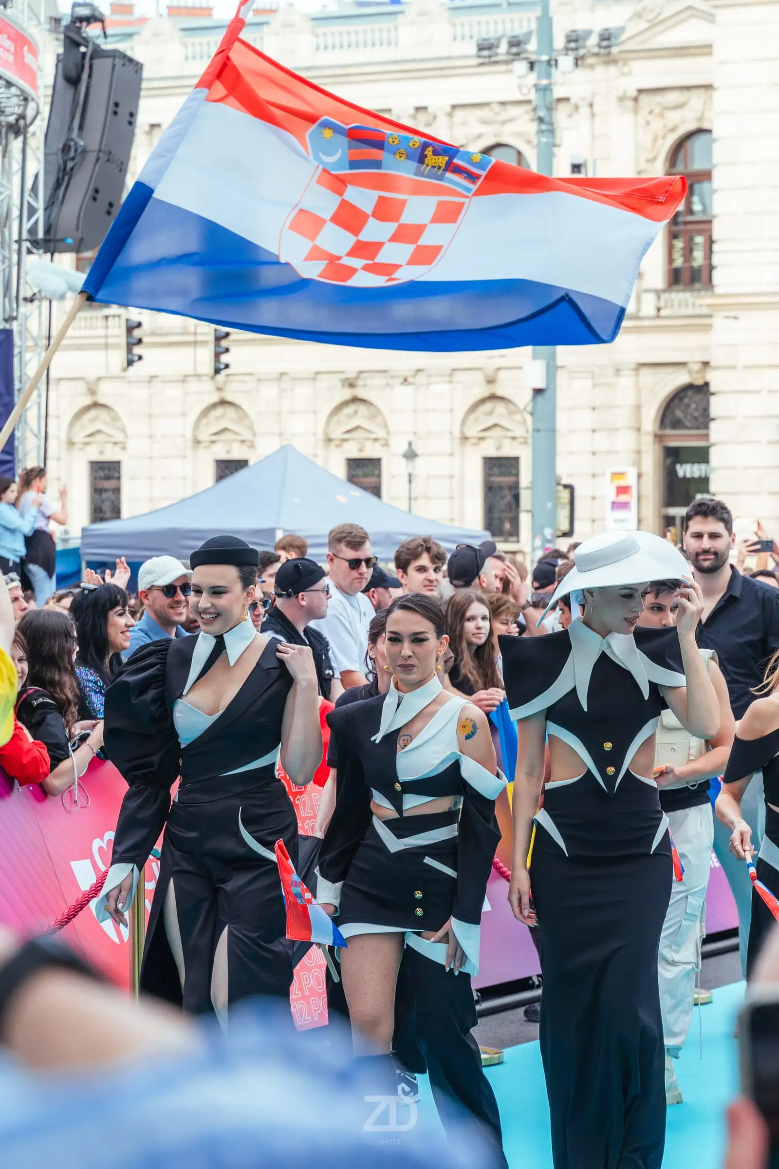 Künstlergruppe in schwarzen Outfits vor Menschenmenge