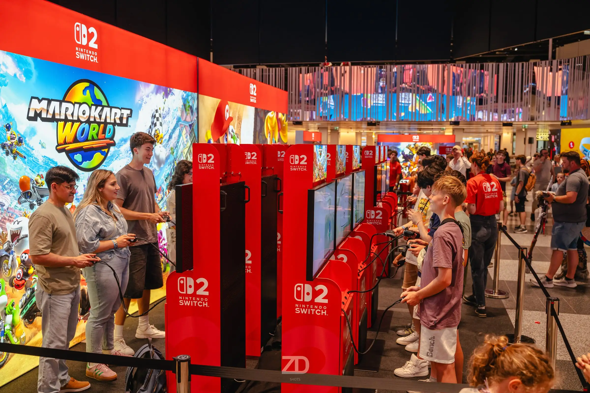 Besucherinnen und Besucher spielen an einer Reihe von Konsolen auf einer Gaming-Messe