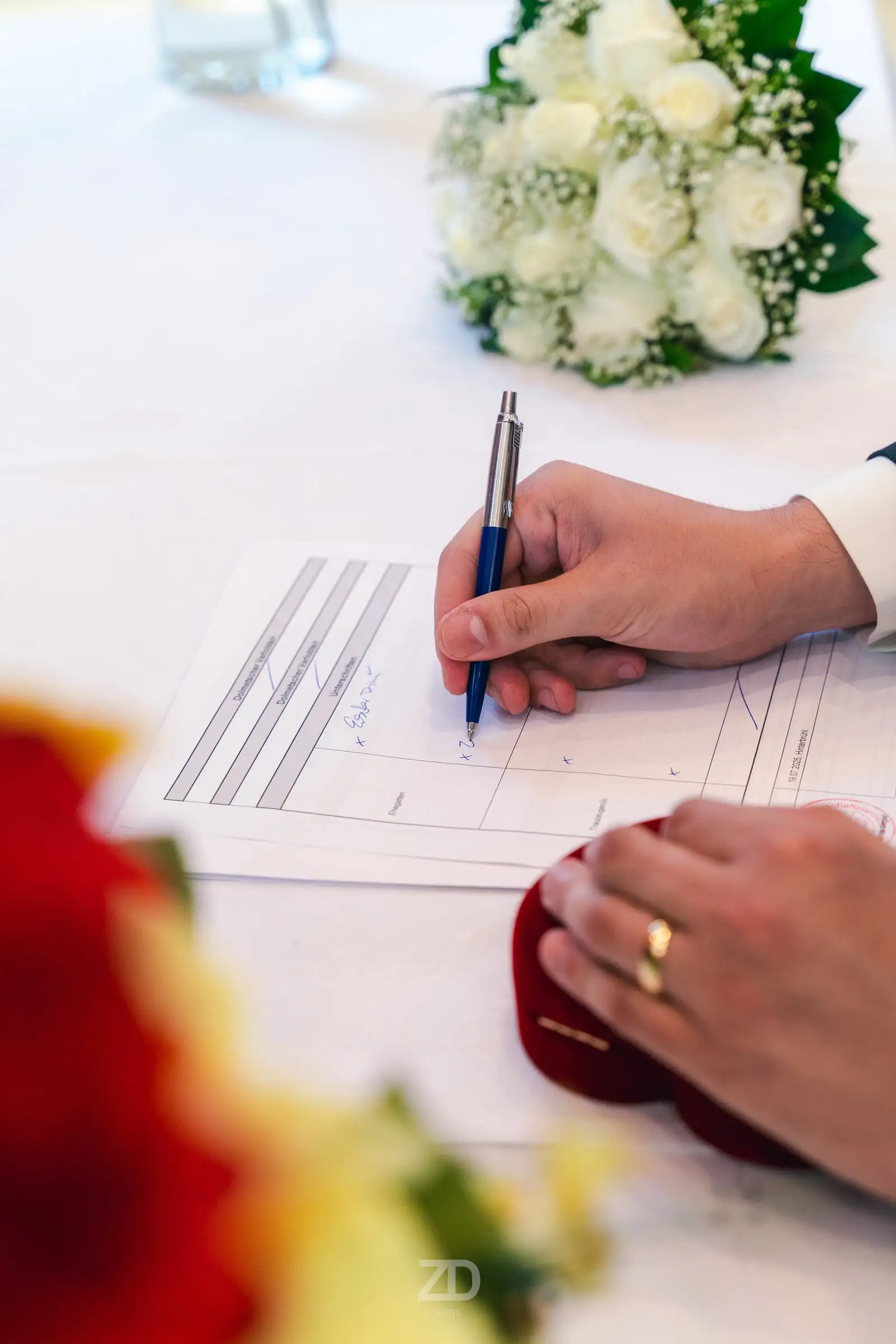 Unterschrift auf der Heiratsurkunde neben dem Brautstrauß