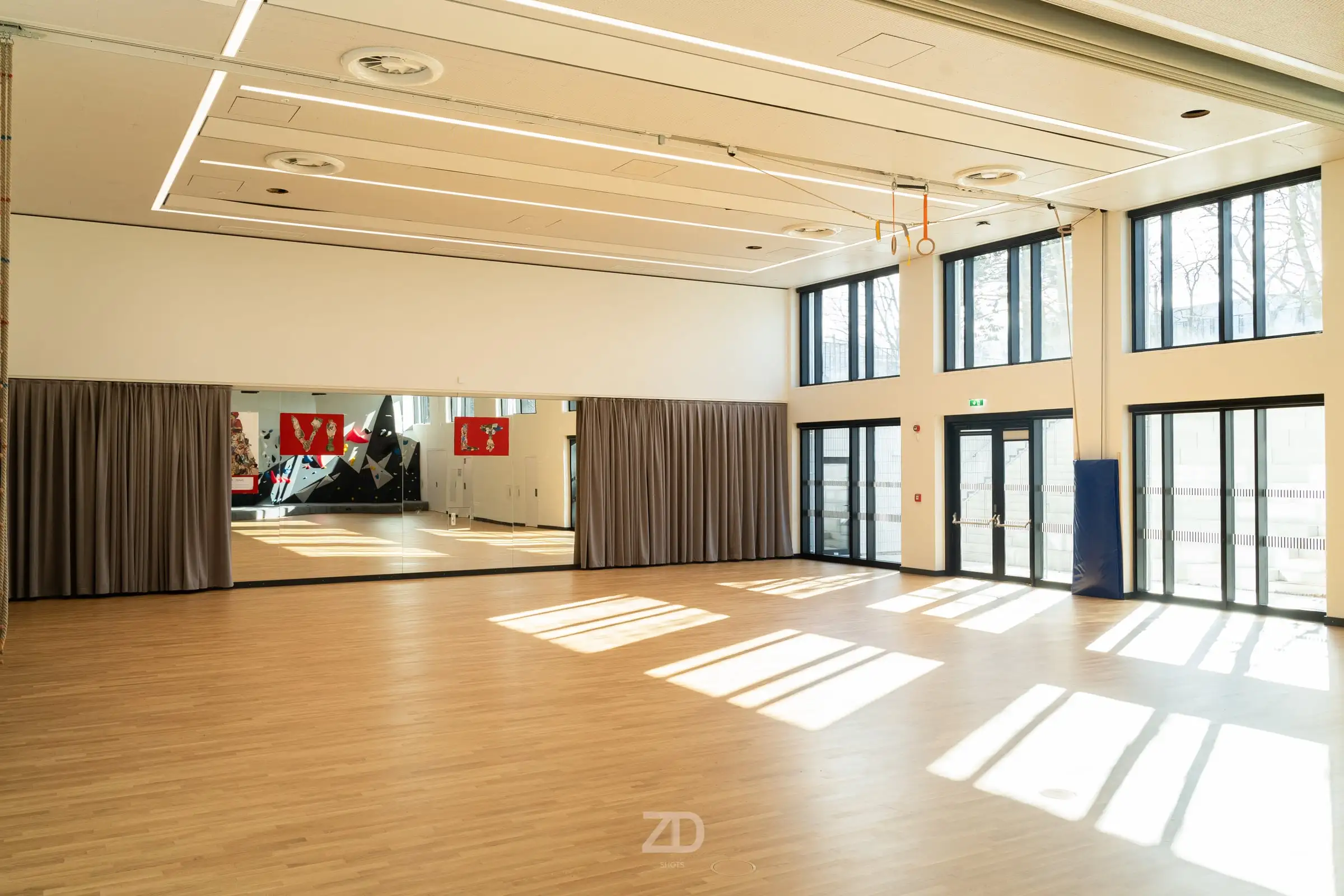 Großer Saal mit Parkettboden und Sonnenstreifen