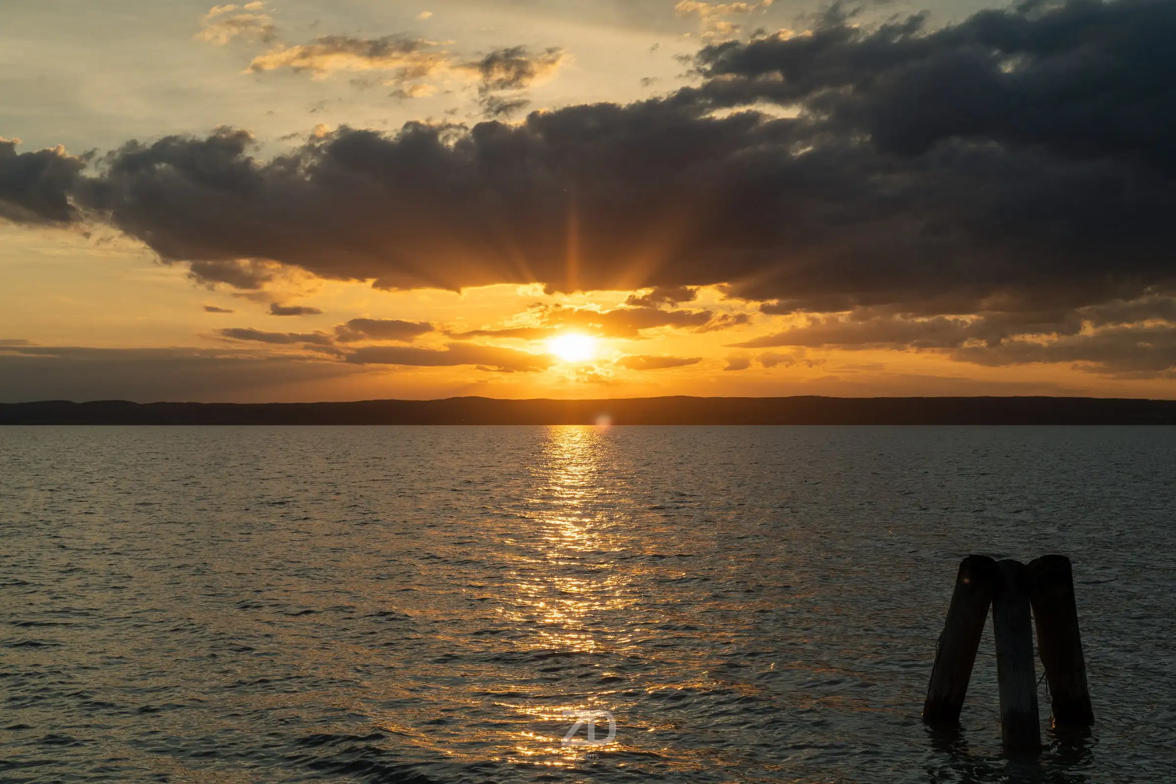 Sonnenstrahlen über einem See mit Holzpfählen