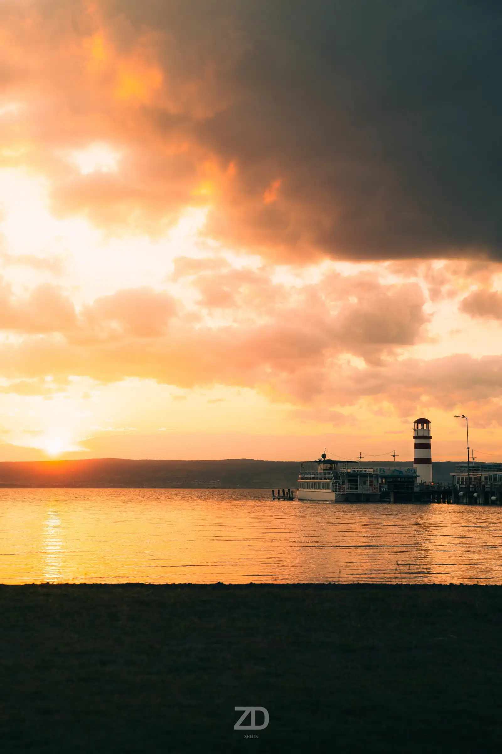Sonnenuntergang über einem See mit Leuchtturm