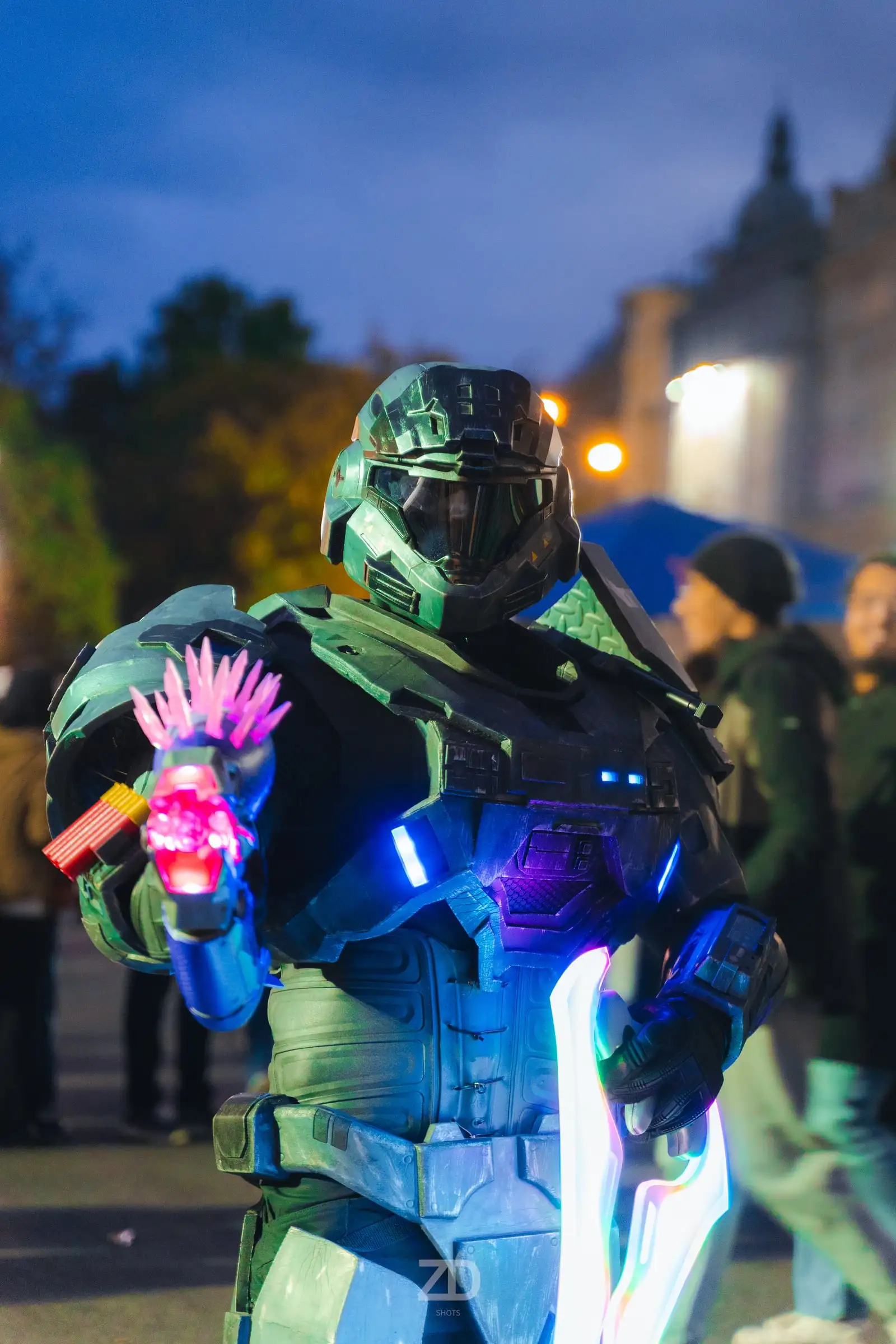 Cosplayer in grüner Rüstung mit leuchtenden Details am Abend