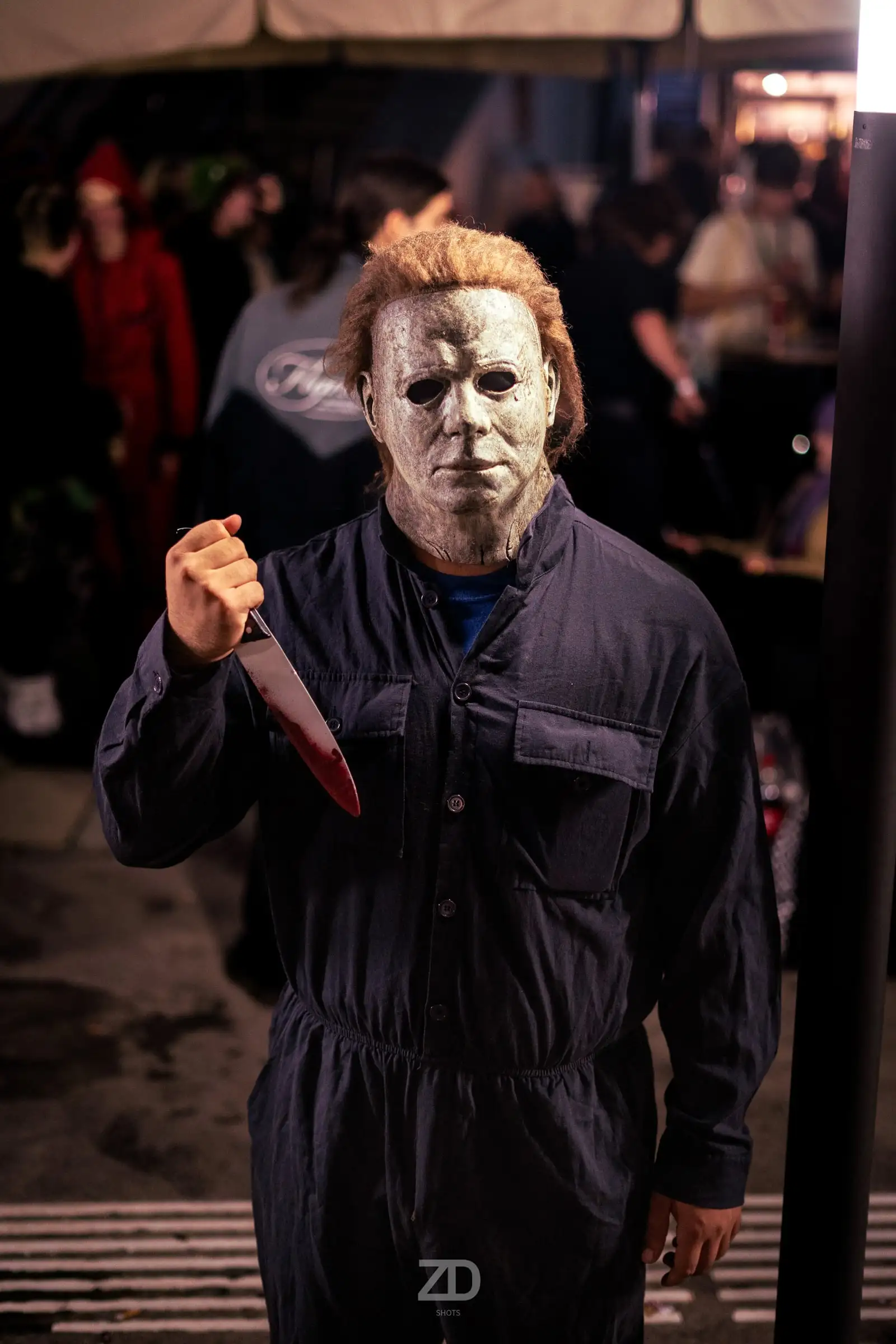 Kostüm mit weißer Maske und Overall in dunkler Umgebung