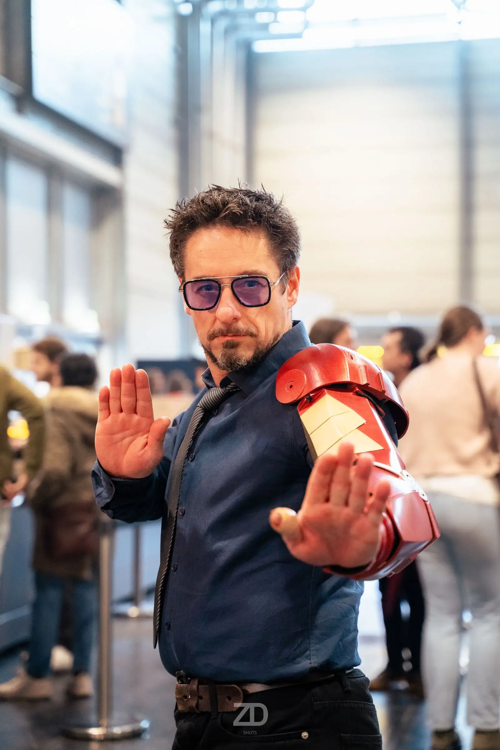 Cosplayer als Tony Stark mit Rüstungshandschuh, die Hände zur Kamera gestreckt