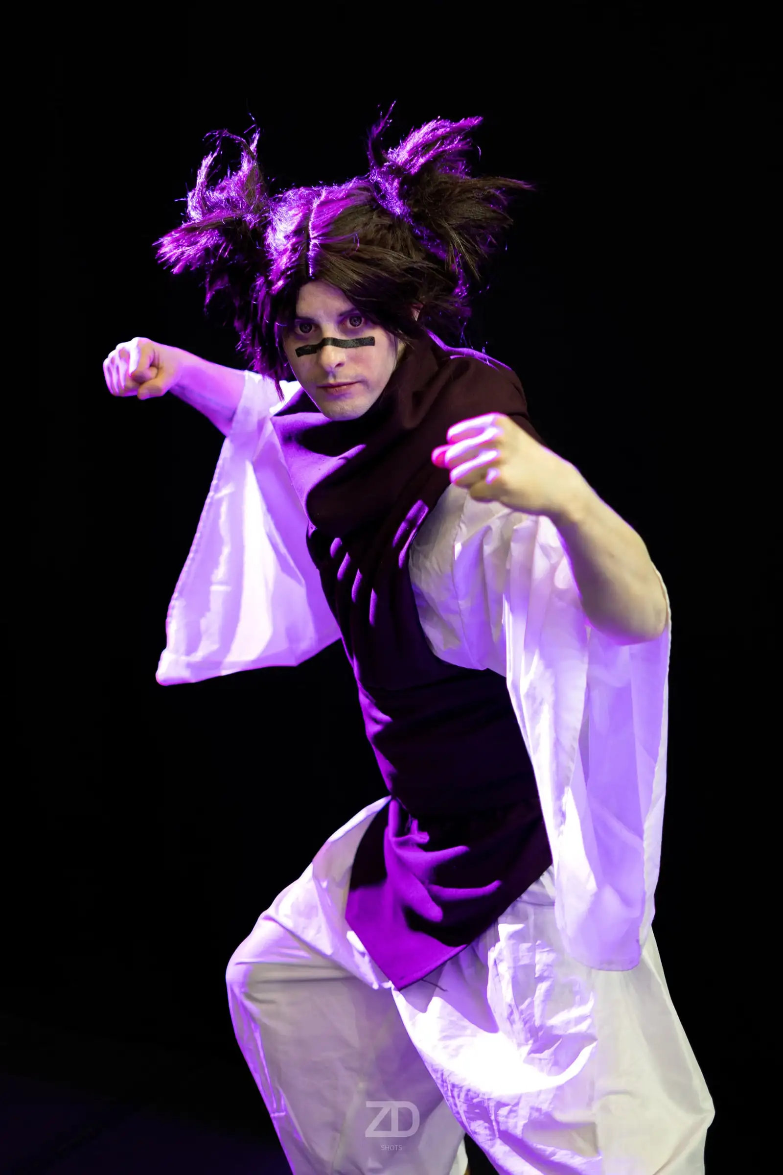 Cosplayerin in violettem Kostüm vor schwarzem Hintergrund