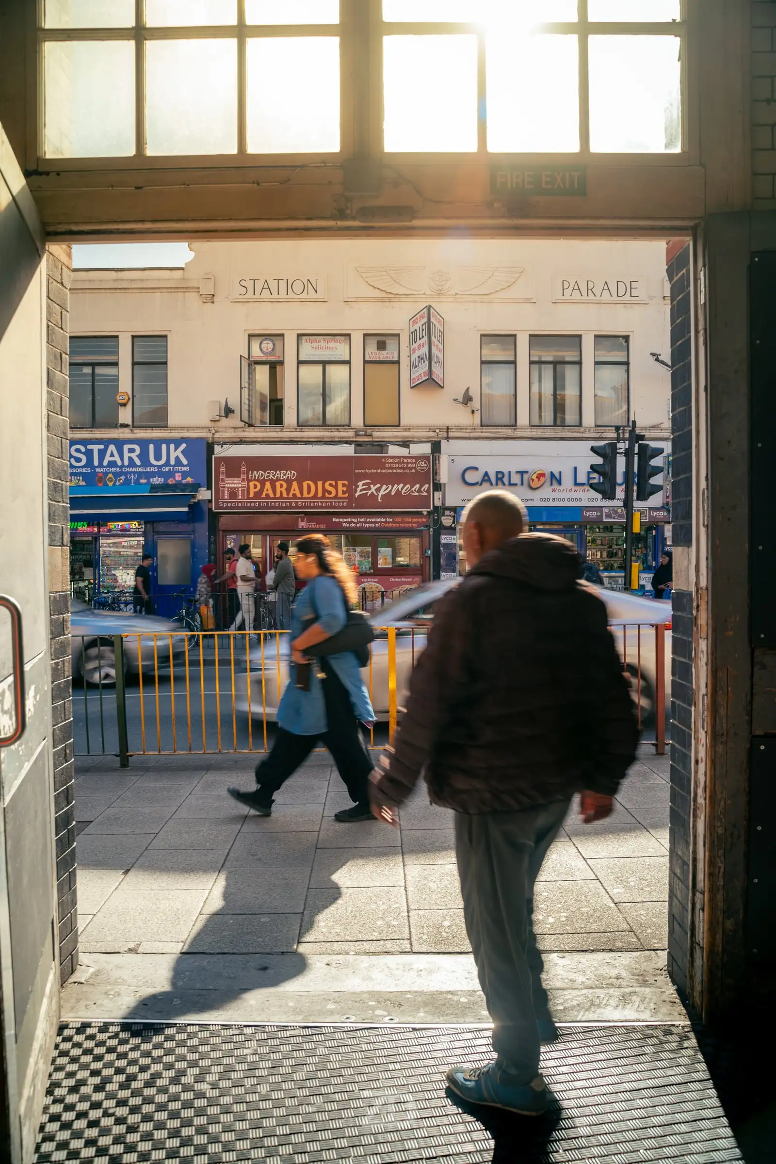 Passanten im Gegenlicht an einer Tür zur Straße