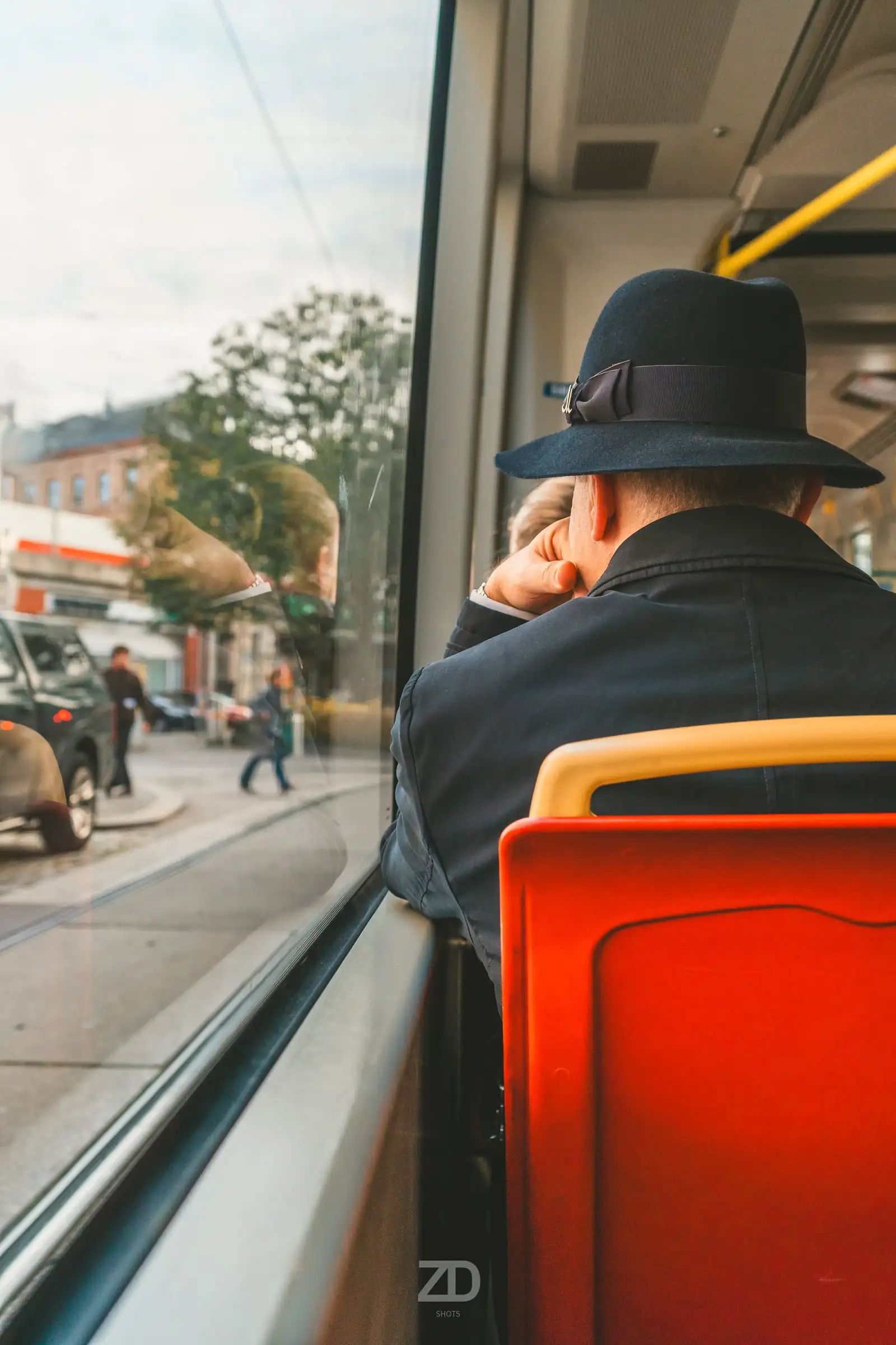 Fahrgast mit Hut am Fenster einer Straßenbahn