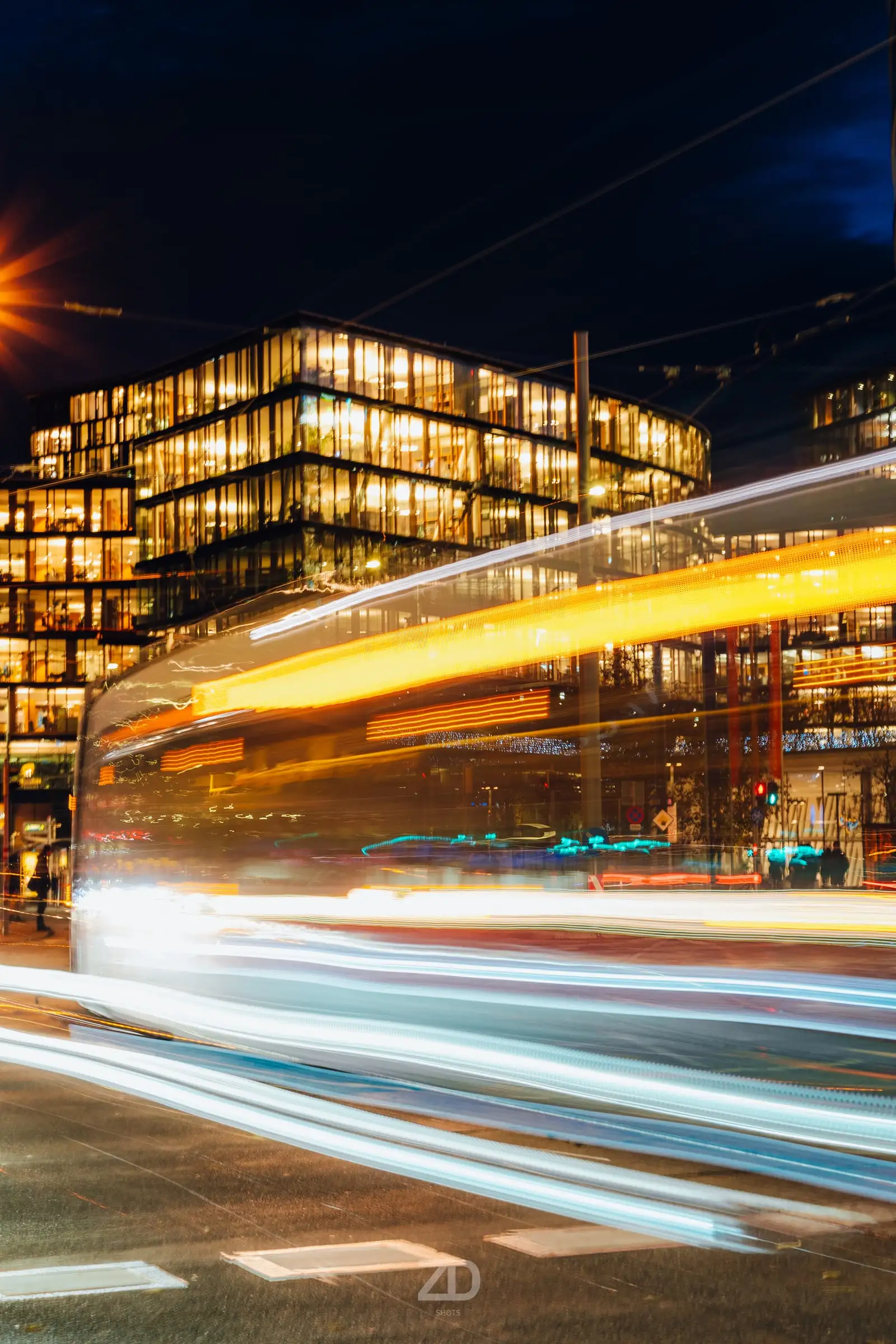 Lichtspuren vor einem beleuchteten Gebäude bei Nacht