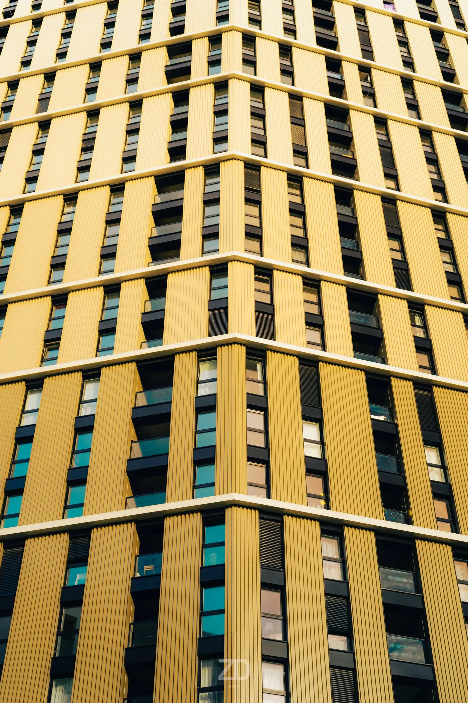 Gelbe Fassade eines Hochhauses mit vertikalen Streifen