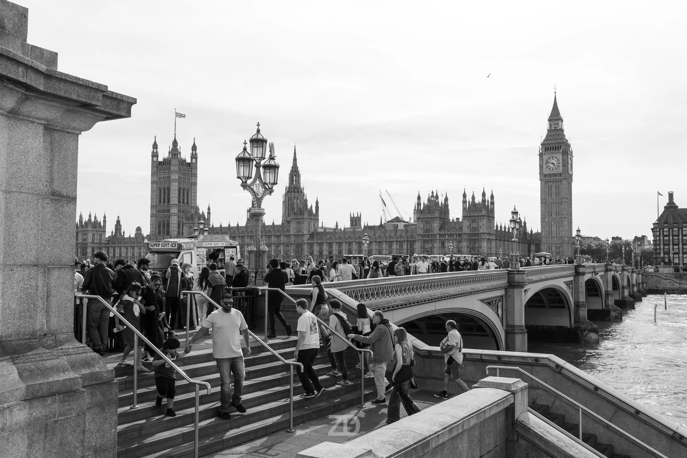Menschen auf Stufen am Fluss mit Parlament und Uhrturm