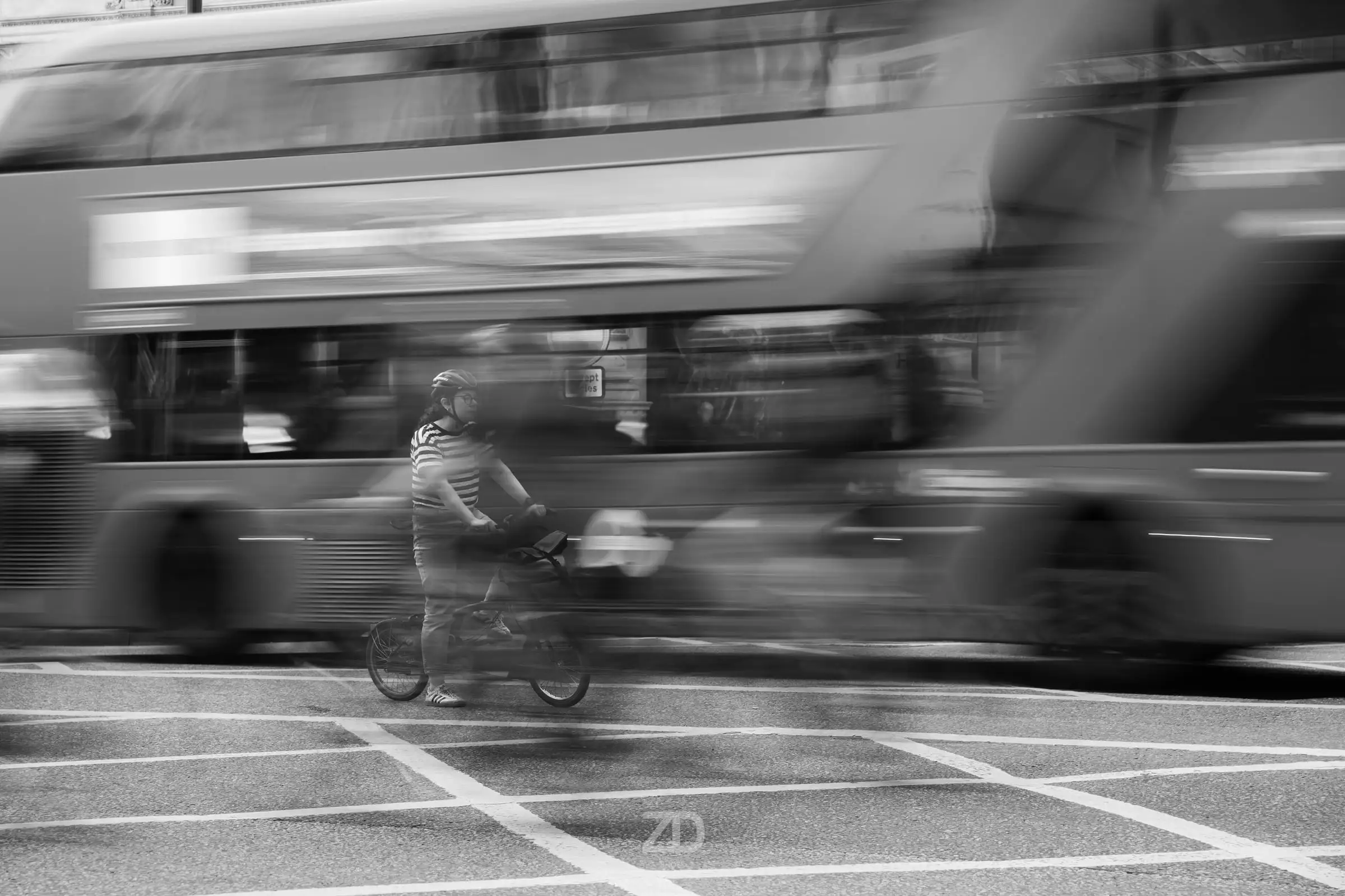 Radfahrer vor einem vorbeifahrenden Doppeldeckerbus mit Bewegungsunschärfe