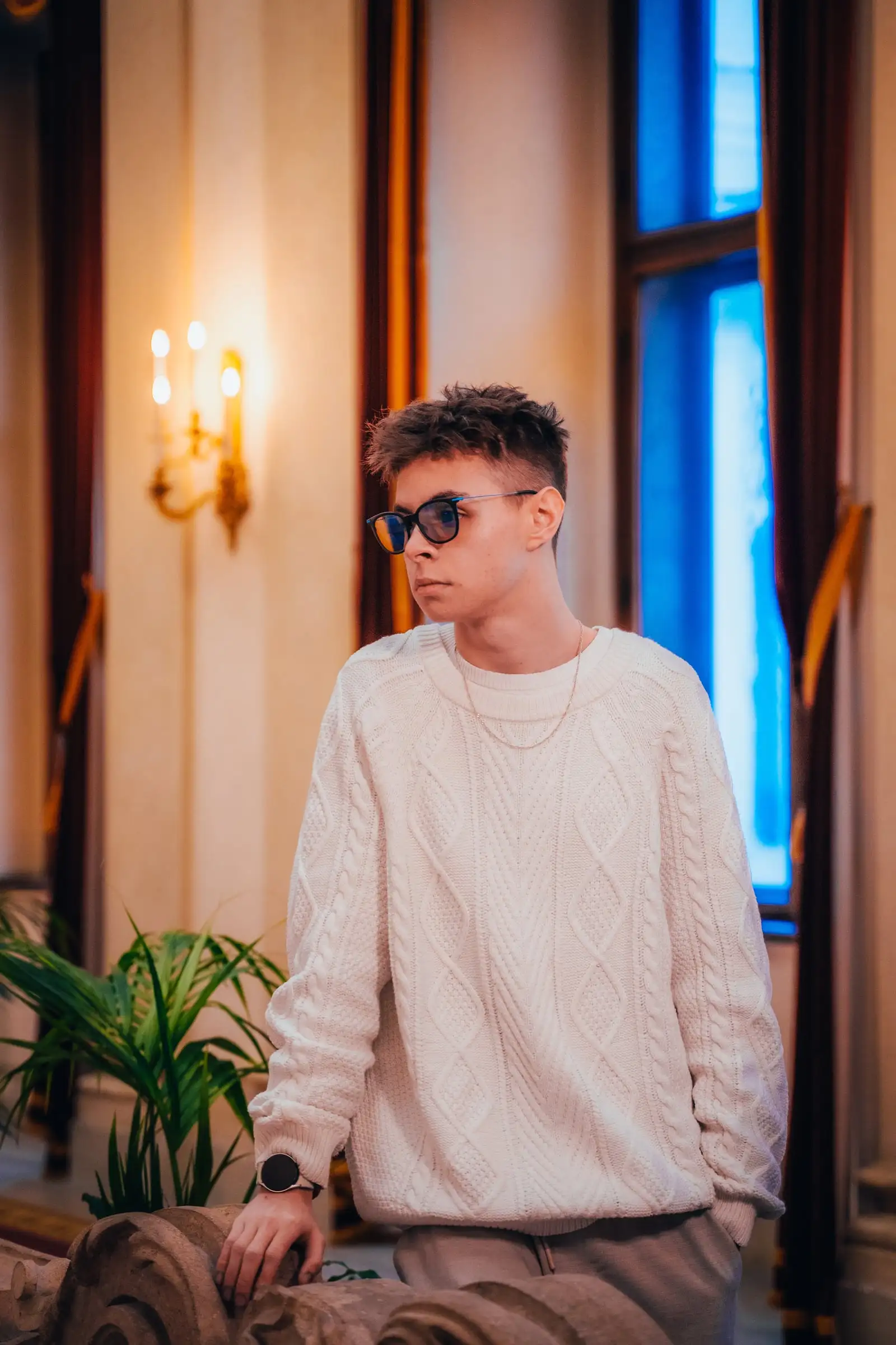 Zeljko Dinic in weißem Strickpullover und Brille in einem historischen Innenraum